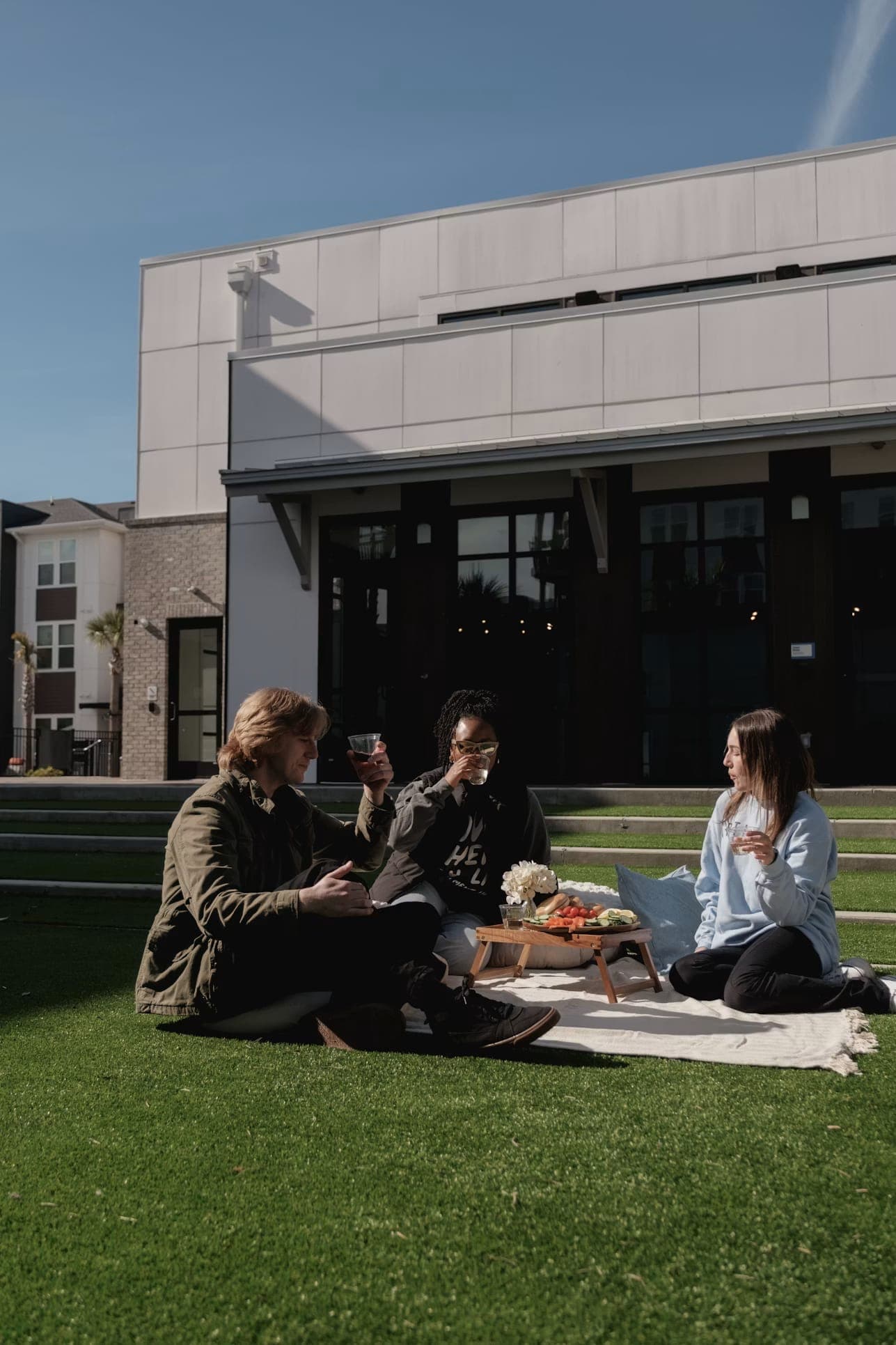 Neighbors sharing a picnic on the lawn outside their building